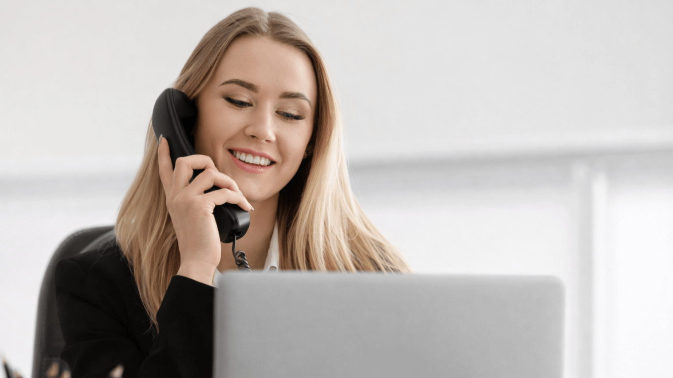 Business professional using a VoIP phone system at her desk, managing customer calls and call queues through a modern business phone system