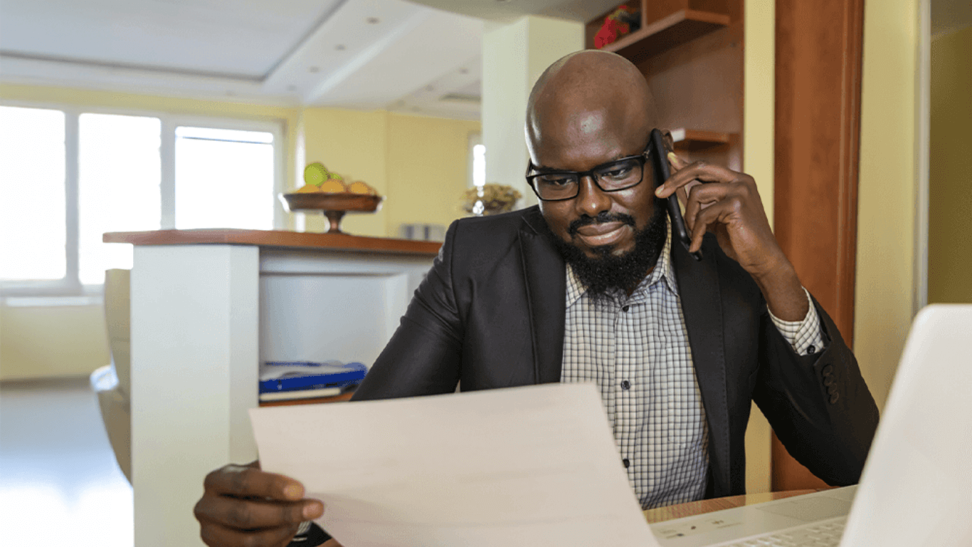 Business professional working remotely, using a VoIP phone solution to handle calls and documents from a home office